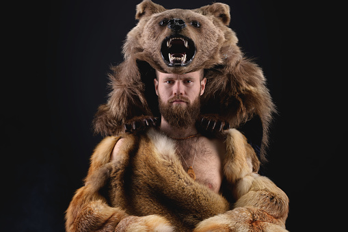 Low key portrait of a bearded military shaman in bearskin. High quality cosplay of the ancient werewolf war.