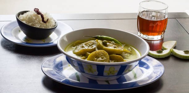 Traditional kashmiri cuisine, Al Yakhni is a yoghurt based gravy that has mild, aromatic herbs and spices like - cardamom, cinnamon,tumeric. This Indian dish is served with steamed rice and Kashmiri herbal tea called kahwa during festivities.This vegetarian dish is made with calabash also called bottle gourd, has rich texture,mild flavors,aroma and taste. Served here in blue bowls,plates, placed on a brown wooden table, this gravy is a delicacy from India.Front view,closeup al yakhni, una cocina vegetariana de cachemira de la india es una salsa a base de yogur. hecho de calabaza también llamada como calabaza de botella es de sabor suave, aromático, retroiluminado. servido con arroz y té de hierbas de cachemira a saber, kah