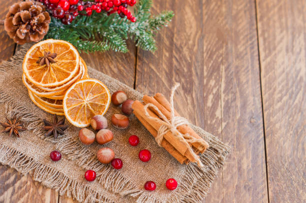 istock Christmas composition with spruce tree branches, cinnamon sticks, dried slices of oranges, nuts and anise on wooden background. Rustic style. 1332321286