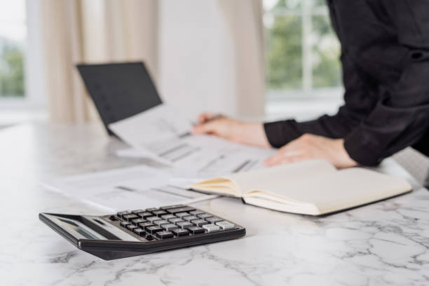 istock Woman calculating expenses while standing behind table 1332325476
