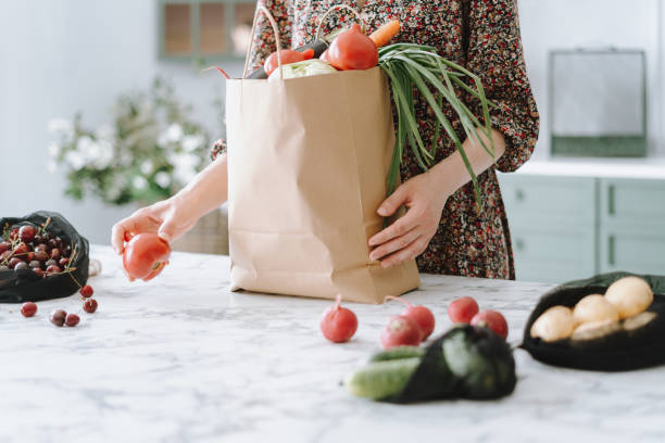 紙の食料品袋から野菜を開梱する女性 - paper bag groceries food vegetable ストックフォトと画像