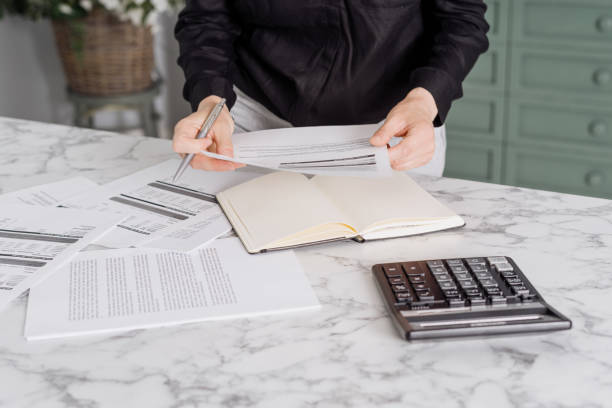 istock Person holding invoice paper while standing in kitchen 1332325746