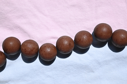 Spherical chocolates arranged in a row, pastel-colored background