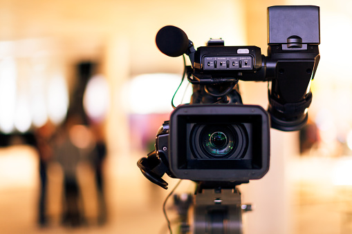 Front view of a professional video camera with blurred background