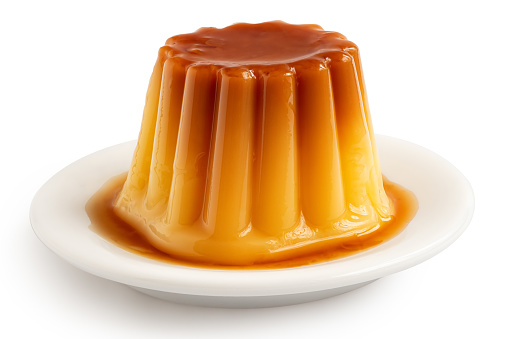 Caramel flan with syrup on white ceramic plate isolated on white.