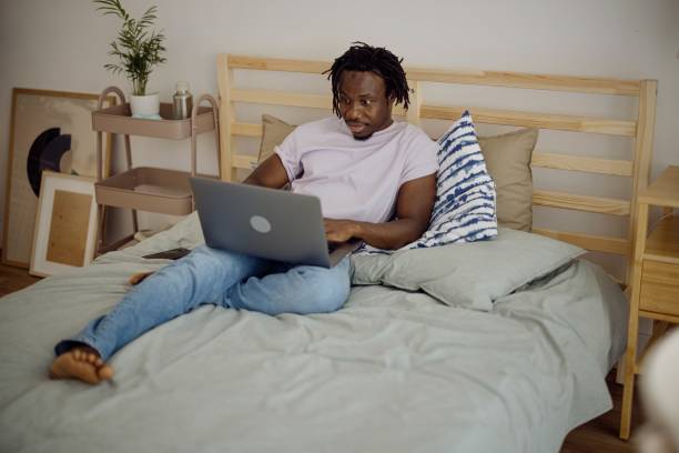 istock Man in bed working on a laptop computer. The student prepares for the exams and learns via computer 1332337846
