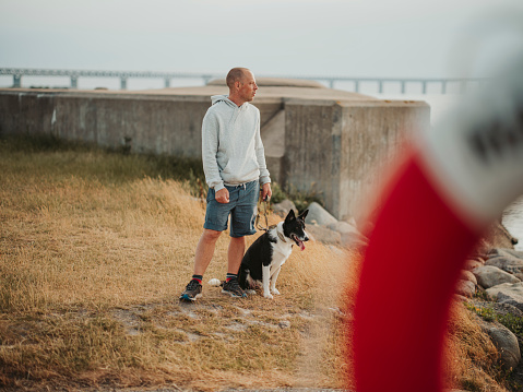 Man and his dog at the beach by the ocean sea. Candid photo taken outdoors in summer.