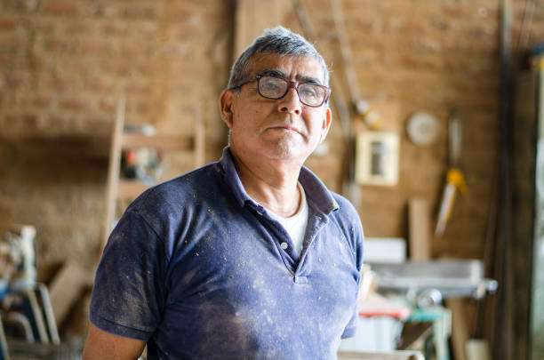 Portrait of an elderly carpenter posing and his workshop in the background. stock photo