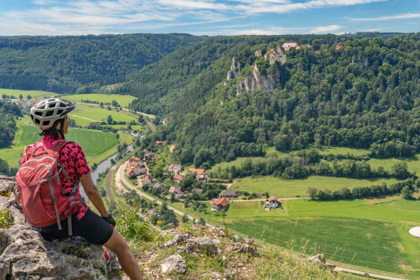 senior woman with electric mountain bike in the Danube Valley, Germany beautiful active senior woman cycling with her electric mountain bike in the rocky Upper Danube Valley on the Swabian Alb between Beuron and Sigmaringen danube valley stock pictures, royalty-free photos & images