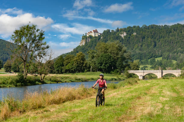 senior woman with electric mountain bike in the Danube Valley, Germany beautiful active senior woman cycling with her electric mountain bike in the rocky Upper Danube Valley on the Swabian Alb between Beuron and Sigmaringen danube valley stock pictures, royalty-free photos & images