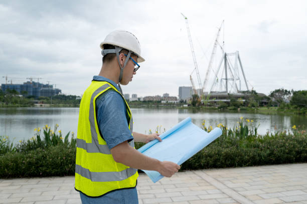 istock Side view of male engineer looking at blueprints at construction site 1332339469
