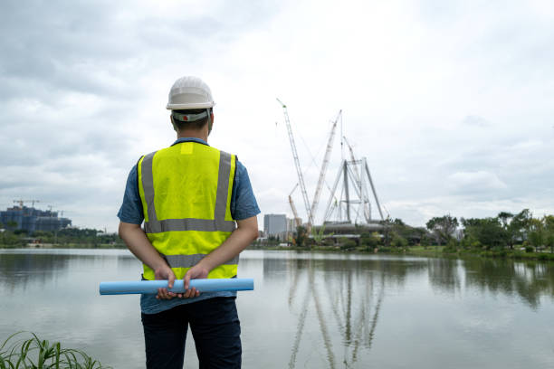 Back view of male engineer holding blueprint at construction site