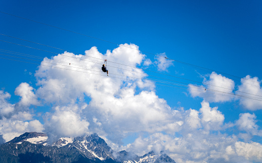 Having fun on a zip line in the mountains against beautiful clouds