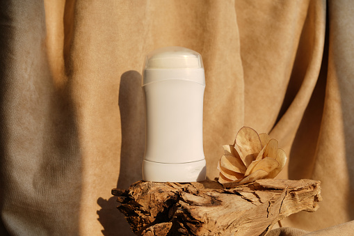 natural Deodorant or antiperspirant on wood podium with flower and sunlights