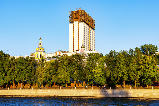 The high-rise building of the Russian Academy of Sciences and the St. Andrew's Monastery. View of buildings from the water of the Moskva River on a sunny summer evening - Moscow, Russia, June 2021