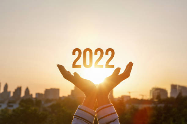 istock 2022 is supported by hands on the background of a sunny sunset. 1332352372