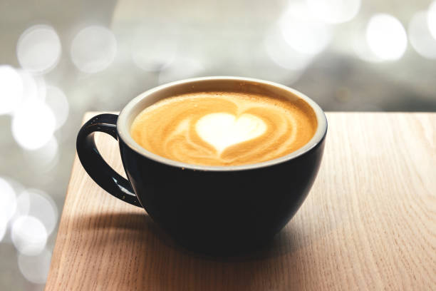 Cup of coffee on wooden table with blurred lights bokeh