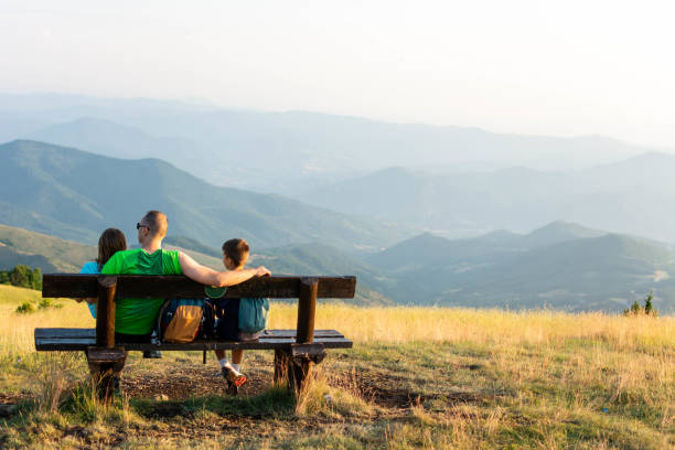 istock Father and children sitting on the bench having relaxing conversation. 1332354302