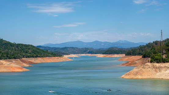 Recreational boats on Lake Shasta, California during drought. Houseboats and other recreational vehicles on Shasta Lake, California during drought. Water level is about 100 feet/30 meters below full capacity exposing barren shoreline. June 21, 2021.