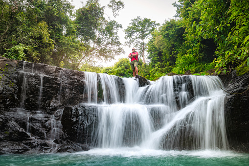 tourist trekking to waterfall in tropical forest during holiday. Holiday activities.