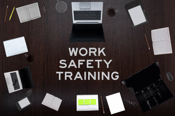 istock Work safety training concept. Top layout of drawings of laptops, notepads, coffee, different business stuff on table background. 1332354493