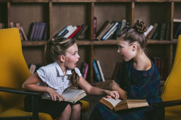 Children girls in the library with books in a strict fashion in education Children girls in the library with books in a strict fashion in education concentrated solar power stock pictures, royalty-free photos & images