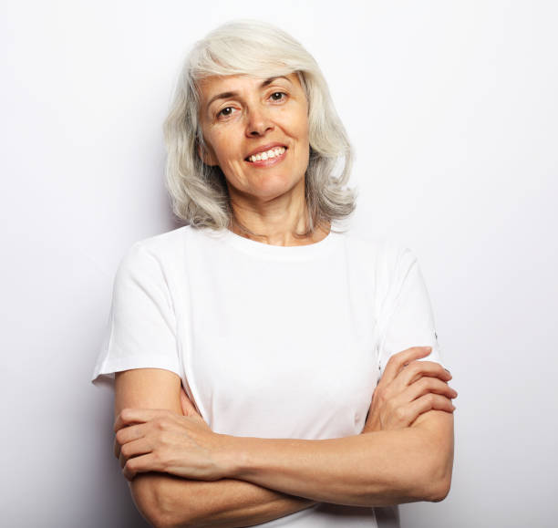 Portrait of senior gray-haired woman with cute smile over white background stock photo