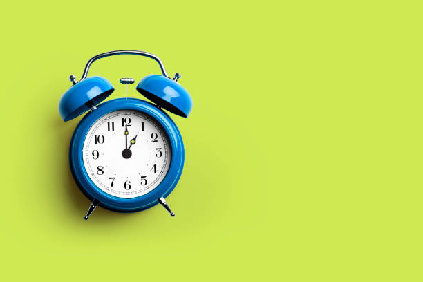 istock Blue retro alarm clock on green background 1332357475
