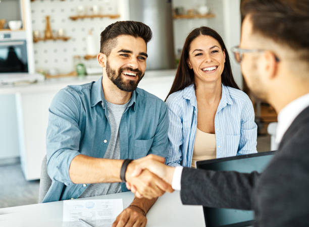 young couple shaking hands deal contract real estate investment business agreement agent handshake signing Real estate agent with couple shaking hands closing a deal and signing a contract house rental photos stock pictures, royalty-free photos & images