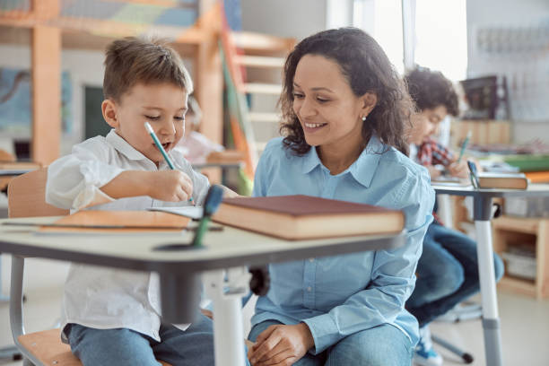 istock Happy kind teacher is helping a boy in elementary school lessons 1332359743