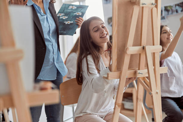 istock Young creative happy pupils at light modern classroom are doing drawing lesson 1332359765
