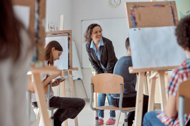 istock Smiling happy female mixed race teacher is looking on a pupil's drawing work 1332359777
