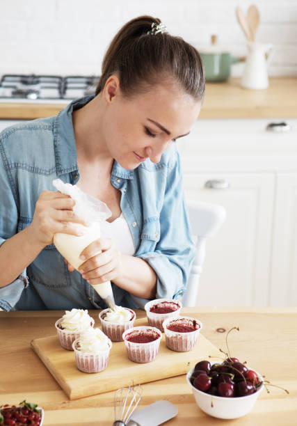 istock A young woman decorates muffins with white cream in her kitchen 1332361872