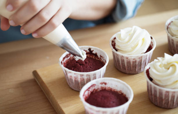 istock A young woman decorates muffins with white cream in her kitchen 1332361880