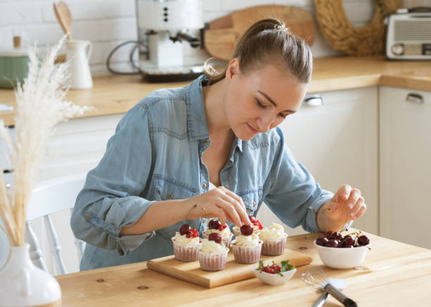 istock Young woman pastry chef decorates cupcakes with berries 1332361919