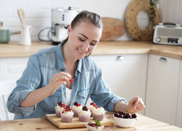 istock Young woman pastry chef decorates cupcakes with berries 1332361921