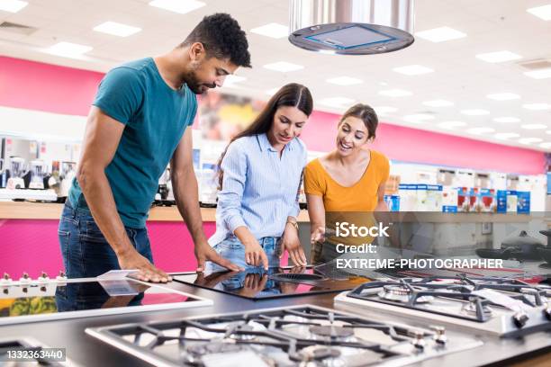 Young Couple Receiving Assistance From A Saleswoman Stock Photo - Download Image Now
