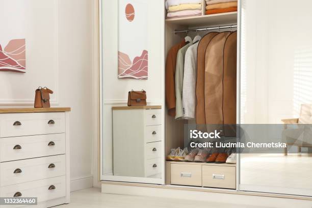 Garment Bags With Clothes On Rack In Wardrobe Indoors Stock Photo - Download Image Now