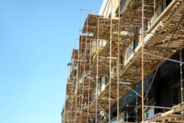 istock View of unfinished building with scaffolding against blue sky, space for text 1332364528