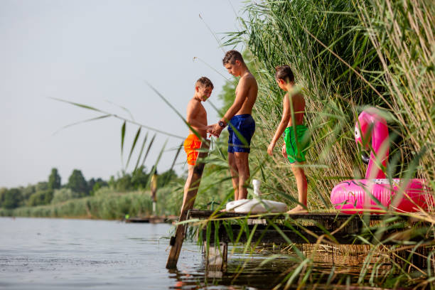 istock Three boys ,wet of river water, talking and smiling on jetty. 1332364538
