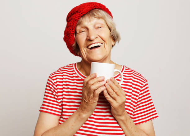 istock old excited lady smiling laughing, holding cup drinking coffee or tea 1332365299