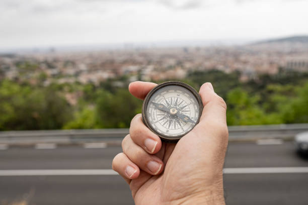 istock hand holding a compass, and a city in the background 1332366349