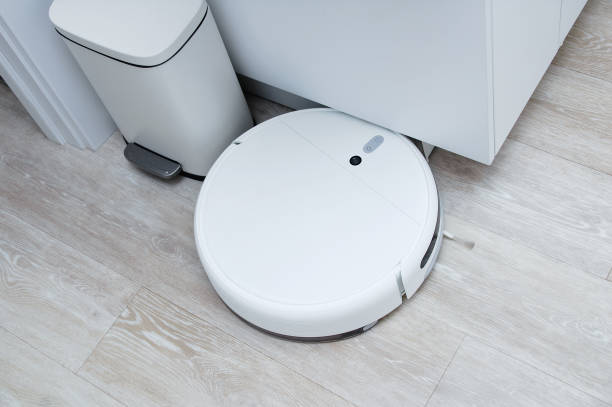 istock White robot vacuum cleaner collided with an obstacle on kitchen floor. 1332372476