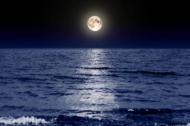 istock Full moon in the dark sky above the water 1332373873