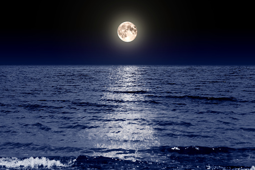 Full moon in the dark sky above the water