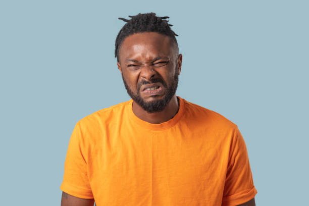 Young man with a disgusting expression, Human emotions, facial expression concept.
Blue color background, Studio shot .
