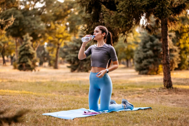 istock Woman drinking water after training in park 1332377367