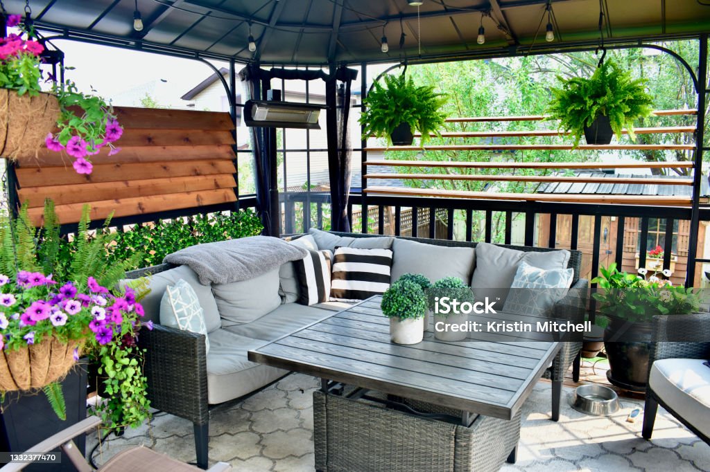 Outdoor backyard sheltered patio seating with a tropical Caribbean feel for summer relaxation Beautiful seasonal outdoor living room with lush greenery and flowers for spring and summer staycation relaxing. Back Yard Stock Photo