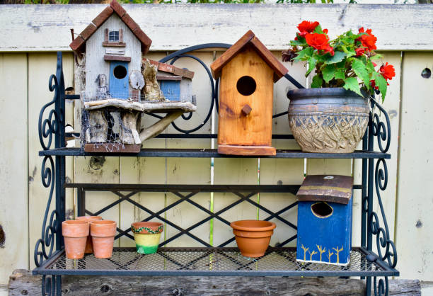 pajareras decorativas en el patio trasero al aire libre dispuestas en una mesa de macetas de hierro - birdhouse bird house ornamental garden fotografías e imágenes de stock