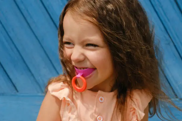 A cute four-year-old girl with a vestibular hard mouthguard plate for correcting the bite of teeth in orthodontics. Children's orthodontic mouthguard. myofunctional trainer. mouth breathing habit